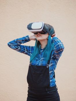 Street punk or hipster girl with blue dyed hair having fun with vr glasses. Carefree concept. Virtual reality concept. Slow motion.