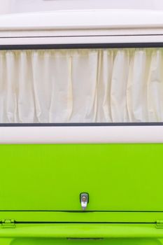 Curtained window of a bright white and green retro Volkswagen van close up