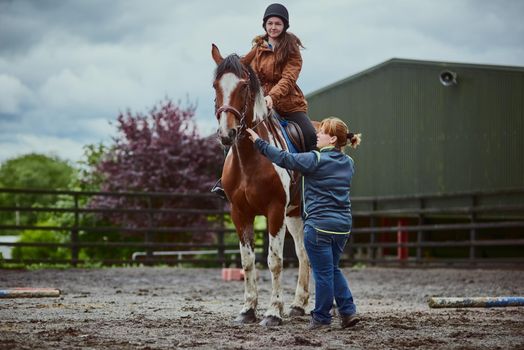 Nothing says childhood dream like learning to ride a pony. a trainer teaching a teenage girl how to ride a horse on a farm