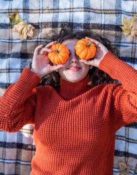 Leisure, free time. Beautiful caucasian woman in red sweater on a picnic outdoors, sitting on a plaid in autumn forest