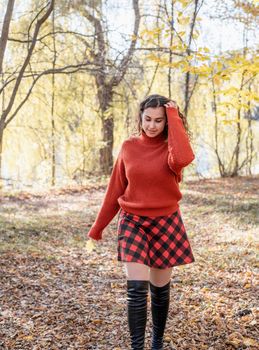 Autumn nature. young happy woman in red sweater and skirt walking in autumn forest