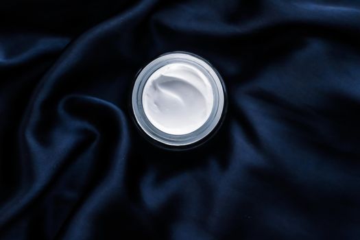 Beauty, anti-age cosmetics and skincare concept - Luxury face cream jar on a dark blue silk