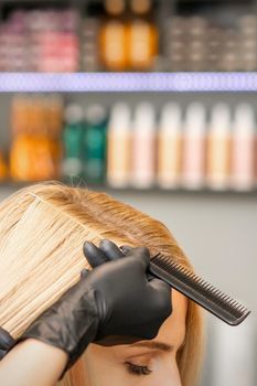 Hairdresser's hand combs female hair before dyeing in a beauty salon