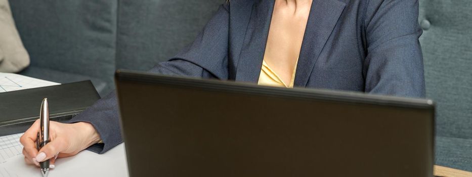 Young businesswoman sitting at the table and writing in a notebook. Adult woman working with papers at the cafe