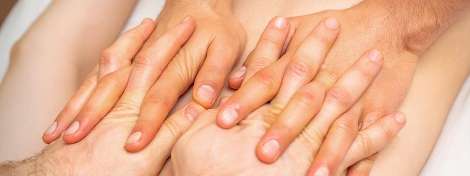 4 hands massage the patient back. Two masseurs doing massage. Closeup