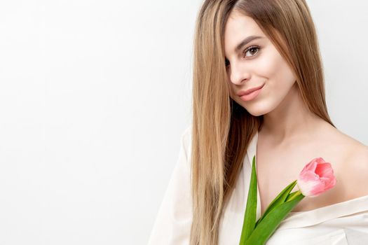 Portrait of a happy young caucasian woman with one pink tulip against a white background with copy space