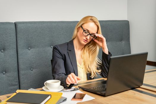 Young businesswoman using laptop sitting at the table in a cafe