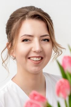 Portrait of a happy young caucasian woman with pink tulips against a white background