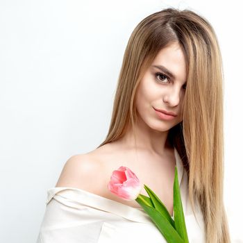 Portrait of a happy young caucasian woman with one pink tulip against a white background with copy space