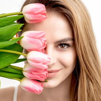 Portrait of a happy young caucasian woman with pink tulips against a white background