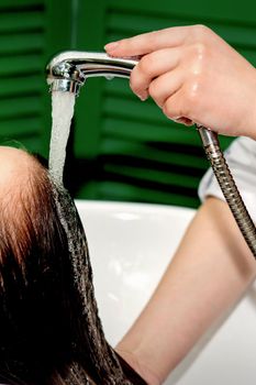 Side view photo of a young caucasian woman receiving washing hair in a hair salon