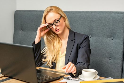 Young businesswoman using laptop sitting at the table in a cafe