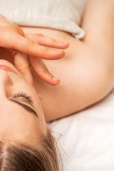 Chin or neck massage of a young woman by the hand of a male massage therapist in a spa salon