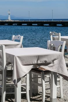 White restaurant tables on the beach in summer - travel, vacation and summer concept. The perfect lunch with a sea view