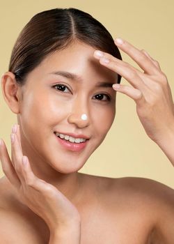 Closeup ardent girl with soft makeup applying moisturizing skincare cream on her face, isolated background. Skincare cream applied by female model concept.