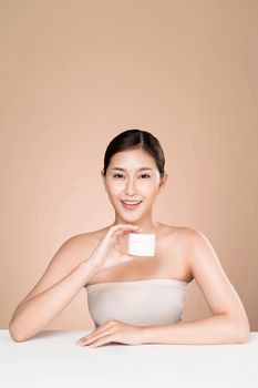 Ardent woman smiling holding mockup product for advertising text place, light grey background. Concept of healthcare for skin, beauty care product for advertising.