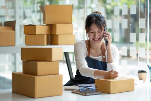 Startup small business entrepreneur SME, asian woman receive order on phone. Portrait young Asian small business owner home office, online sell marketing delivery, SME e-commerce telemarketing concept.