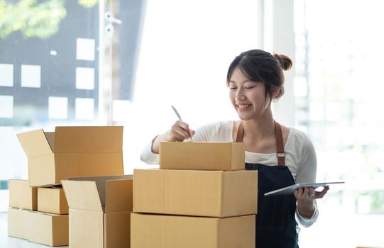 Portrait of Asian young woman SME working with a box at home the workplace.start-up small business owner, small business entrepreneur SME or freelance business online and delivery concept..