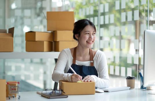 Small start-up business owners using computers and phones at work, salespeople, checking production orders. Pack products to ship to customers, sell ecommerce shipping ideas..