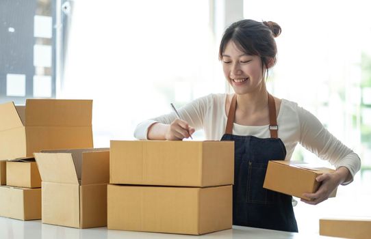 Portrait of Asian young woman SME working with a box at home the workplace.start-up small business owner, small business entrepreneur SME or freelance business online and delivery concept..