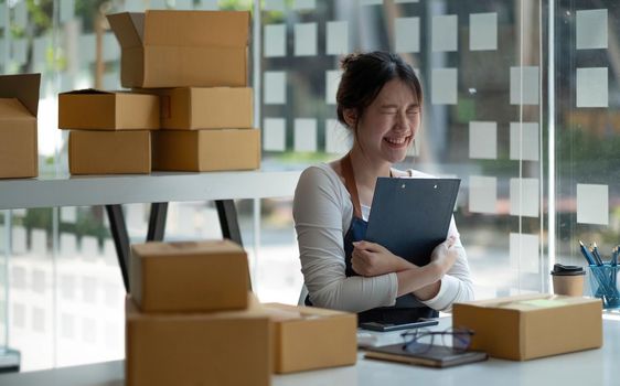 Startup SME small business entrepreneur of freelance Asian woman using a laptop with box Cheerful success Asian woman her hand lifts up online