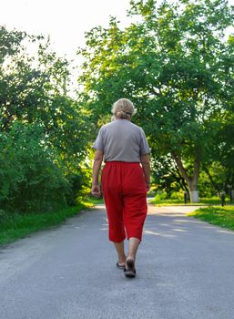 grandma is walking down the road. Selective focus. Nature.