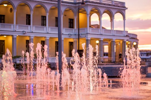 Street fountains near the building in the park in the sunset light. Evening walk around the city