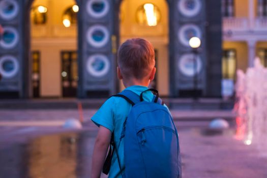 Children have fun frolicking in the fountains near the building in the park in the sunset light. Evening walk around the city