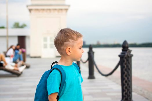 A boy in a blue T-shirt with a backpack on his back. Journey.  The face expresses natural joyful emotions. Not staged photos from nature.