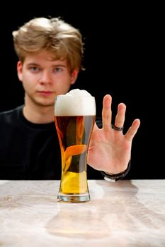 No alcohol. Young man refuses to drink beer. Stop drinking. Say no to alcohol . Black Background