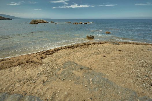 Detail of a portion of sandy beach overlooking the sea with the rocks inside.