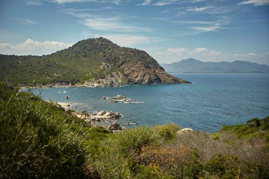 Panoramic view of a natural bay with the sea and the mountains and Mediterranean vegetation in southern Sardinia in Italy, specifically the beach of Cala Sa Figu