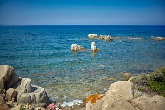 Postcard with blue sea and some pebbles that emerge from the water in the south of Sardinia.