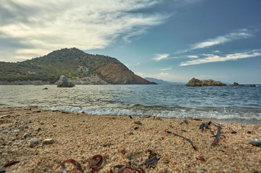 Shooting from the ground of a typical central Mediterranean beach: magnificent seascape with the sand of the beach in the foreground with the sea and the background mountains.