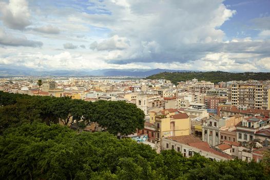 Aerial view of Cagliari's cityscape under a cloudy sky.