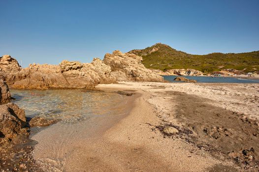 Beautiful aerial view of the Cala Sa Figu beach in Sardinia with its crystal clear sea that meets the colored sand in a spectacular background of the rocky mountains typical of that coast.