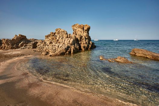 South rocky sardinia beach with waves of transparent sea coming ashore to merge with golden beach.