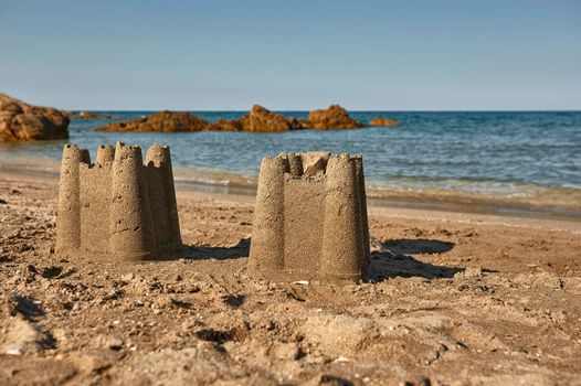 Pair of sand castles built on the golden sands of Cala Sa Figu beach in the south of Sardinia.