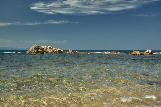 Rocky range of cliffs coming out of the crystal clear water of the southern sea of Sardinia in a summer day.