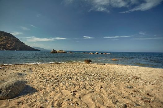 view of a mediterranean beach with the sea in front resumed during sunset.