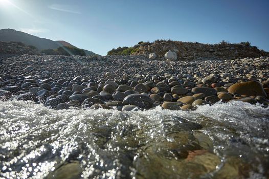 The crystalline water of the southern sea of Sardinia meets with the rocky beach breaking on the pebble stones.