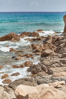 Vertical shot of a cliff that plunges into the rough and wavy sea.