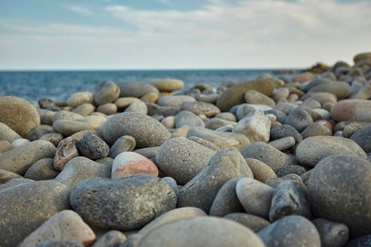 Detail of some white pebbles on a typical beach of the southern coast of southern Sardinia in Italy, with the background of the rest of the beach and the sea.