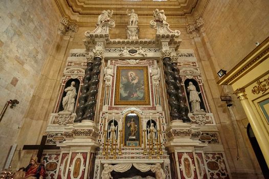 Marble altar inside a church in Cagliari with statues and religious depictions.