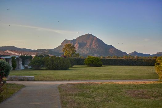 Beautiful garden with a mountain in the background and a path that crosses it: a paradise surrounded by nature in which to relax and enjoy the surrounding landscape.