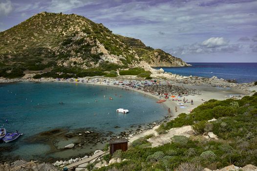 Small beach surrounded by two mountains and the sea front and back in the Mediterranean: Punta Molentis beach.