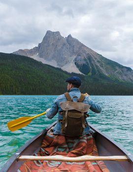 Emerald Lake in Autumn at the Yoho National Park Alberta Canada, men by the Emerald lake Canada. Young men with hat in a canoe at the lake