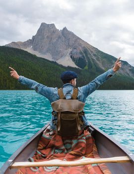 Emerald Lake in Autumn at the Yoho National Park Alberta Canada, men by the Emerald lake Canada. Young men with hat in a canoe at the lake