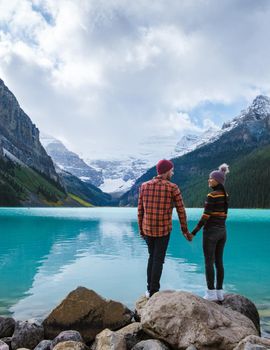 Lake Louise Banff national park, is a lake in the Canadian Rocky Mountains. A young couple of men and women standing by the lake during a cold day in Autumn in Canada