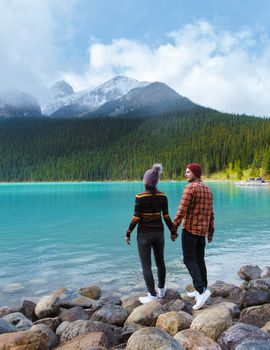 Lake Louise Banff national park, is a lake in the Canadian Rocky Mountains. A young couple of men and women standing by the lake during a cold day in Autumn in Canada